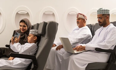 تسجيل وتخليد اللحظات السعيدة، صورة جماعية ، اجراء مكالمة فيديو, عائلة عربيه خليجيه عمانية ترتدي الزي التقليدي تجلس داخل الطائرة فى رحله جوية , رجل خليجي يقوم باستخدام الحاسب المحمول , مفهوم السياحه و السفر