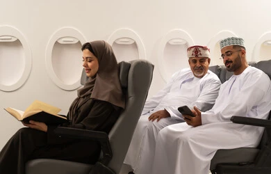 قضاء أوقات ممتعة في القراءة والتثقيف, مشاهده الافلام و المسرحيات عبر الجوال , رجلان عربيان خليجيان عمانيان يرتديان الدشداشة و الكمه يجلسان داخل الطائرة فى رحله جوية , امراة خليجية تقوم بقراءة كتاب,  ايماءات السعادة و السرور , مفهوم السياحه و السفر