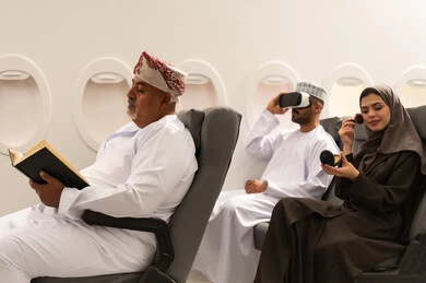 Enjoyment and entertainment in free time, the concept of tourism and travel, a Gulf Arab Omani family wearing traditional attire sitting inside an airplane on a flight, a Gulf woman applying makeup, the concept of tourism and travel.