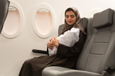 ايماءات الحب و الحنان, الأمومة وحماية الأطفال ورعايتهم, ام عربية خليجيه عمانية ترتدي الحجاب و العباءة تجلس داخل الطائرة فى رحله جويه تحمل رضيع حديث الولادة يرتدي لباس أبيض قطني, مفهوم السياحه و السفر