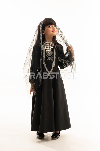 ذكرى تأسيس الدولة السعودية الأولى في 22 فبراير, النظر إلى الأعلى بإيماءات الفخر بالتراث السعودي، ارتداء زي المنطقة الشمالية, يوم بدينا 1727م, بورتريه لفتاة عربية خليجية سعودية مبتسمة ترتدي المحوثل والشيلة, الجسم بالطول الكامل, خلفية بيضاء