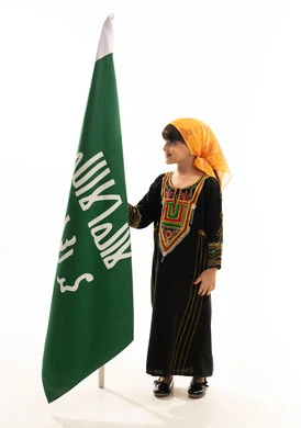 Boasting of belonging to the homeland, the day we began in 1727 AD, the anniversary of the founding of the first Saudi state on February 22, wearing the costumes of the southern region on national occasions, a portrait of a Saudi Gulf Arab girl wearing a sheila and a sidrah holding the founding flag with gestures of pride, full-length body, white background