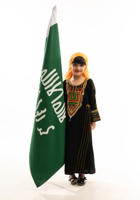 ذكرى تأسيس الدولة السعودية الأولى في 22 فبراير, ارتداء أزياء المنطقة الجنوبية في المناسبات الوطنية, بورتريه لفتاة عربية خليجية سعودية ترتدي الشيلة والسدرة تنظر إلى الكاميرا بإيماءات السعادة وتقف بجانب علم التأسيس, يوم بدينا 1727م, الجسم بالطول الكامل, خلفية بيضاء