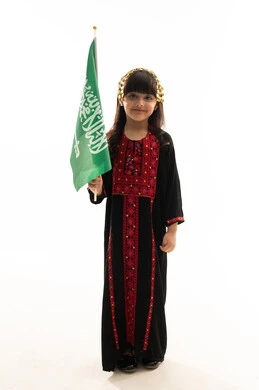 اليوم الوطني السعودي 23سبتمبر، يوم العلم 11مارس، ارتداء زي المنطقة الشمالية, يوم بدينا 1727م, ذكرى تأسيس الدولة السعودية الأولى في 22 فبراير, بورتريه لفتاة عربية خليجية سعودية مبتسمة ترتدي المحوثل تحمل العلم السعودي بفخر وشموخ, الجسم بالطول الكامل, خلفية بيضاء