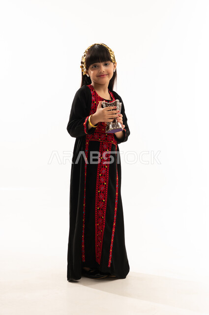 Incense burning using agarwood and incense burner on national holidays, wearing the Northern Region costume, the day of our beginnings in 1727 AD, the anniversary of the founding of the first Saudi state on February 22, a portrait of a smiling Saudi Arabian Gulf girl wearing a muhthal, perfuming and using incense, full body, white background