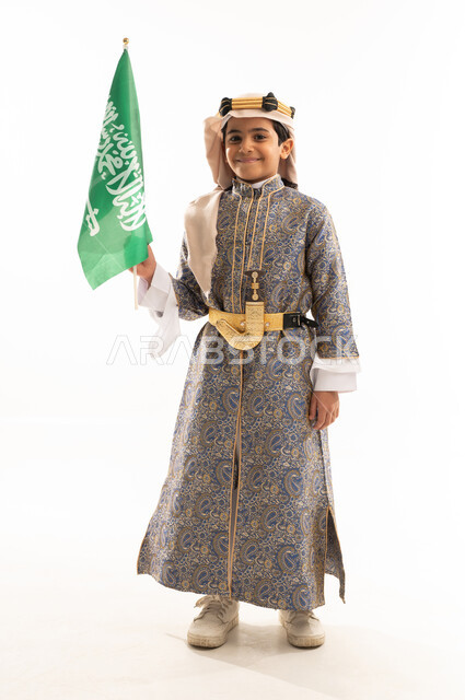 اليوم الوطني السعودي 23سبتمبر، يوم العلم 11مارس، تأسيس الدولة السعودية 22 فبراير، ارتداء أزياء المنطقة الوسطى في المناسبات الوطنية، يوم بدينا 1727 م، بورتريه لولد عربي خليجي سعودي يرتدي الدقلة والخنجر وعقال التأسيس يحمل العلم، صورة لكامل الجسم، خلفية بيضاء
