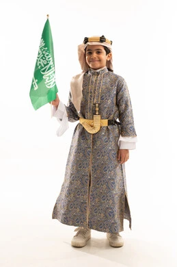 Saudi National Day September 23, Flag Day March 11, Founding of the Saudi State February 22, Wearing the costumes of the Central Region on national occasions, We Began Our Day 1727 AD, Portrait of a Saudi Arabian Gulf boy wearing a dagla, dagger and founding headband holding the flag, full body photo, white background