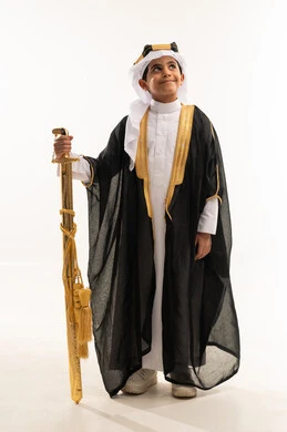 The anniversary of the founding of the Saudi state, February 22, standing up straight and looking up with pride, wearing the costumes of the Eastern Province on national occasions, the day of our beginnings 1727 AD, a portrait of a smiling Saudi Gulf Arab boy wearing a bisht, ghutra, and the founding agal, holding a sword, a full body photo, a white background