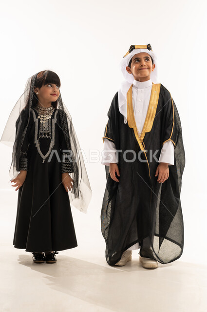 Standing up straight and looking up with proud gestures, Saudi National Day, Saudi traditional costume for national occasions, founding of the first Saudi state, February 22, the day we began 1727 AD, portrait of a smiling Saudi Arabian Gulf boy and girl, full body, white background