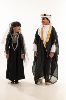 Boasting of the nation's achievements, reviving Saudi heritage, Saudi traditional costume for national occasions, the founding of the first Saudi state on February 22, the day we began 1727 AD, a portrait of a smiling Saudi Gulf Arab boy and girl, full body, white background