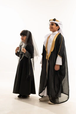 الوقوف باستقامة والنظر إلى الأعلى بايماءات الفخر، اليوم الوطني السعودي، زي تراثي سعودي للمناسبات الوطنية، تأسيس الدولة السعودية الأولى 22 فبراير، يوم بدينا 1727 م، بورتريه لولد وبنت عربيين خليجيين سعوديين مبتسمين، الجسم بالطول الكامل، خلفية بيضاء