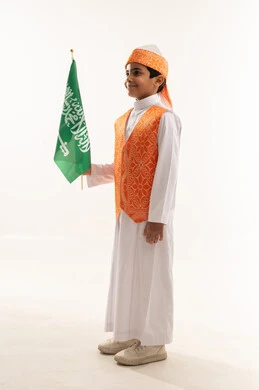 اليوم الوطني السعودي 23سبتمبر، يوم العلم 11مارس، ارتداء أزياء المنطقة الغربية في مناسبة وطنية، يوم بدينا 1727 م، بورتريه من الجانب لولد عربي خليجي سعودي مبتسم يرتدي السديري الشعبي يحمل العلم، تأسيس الدولة السعودية الأولى 22 فبراير، صورة الجسم بالكامل, خلفية بيضاء