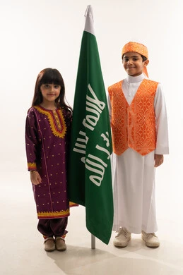 زي تراثي في اليوم الوطني السعودي 23سبتمبر، إظهار الحب والولاء للوطن، ذكرى تأسيس الدولة السعودية الأولى 22 فبراير، يوم بدينا 1727 م، بورتريه لولد وبنت عربيين خليجيين سعوديين مبتسمين يمسكان علم التأسيس، الجسم بالطول الكامل، خلفية بيضاء