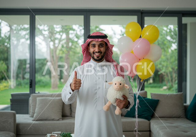 ايماءات البهجة والفرح والسعادة, رجل عربي خليجي سعودي مبتسم يرتدي الثوب التقليدي والشماغ و يحمل بيده دمية على شكل خاروف عيد الاضحى المبارك, أعياد ومناسبات اسلامية, الاحتفال بالعيد السعيد في المنزل