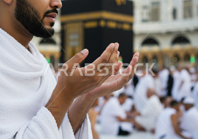 أداء الفرائض والعبادات والتقرب إلى الله, صورة مقربة لأيدي رجل مسلم يلبس ثياب الإحرام ويرفع يديه للدعاء والتضرع امام الكعبة المشرفة,  توجه المسلمين لأداء مناسك الحج والعمرة