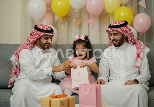  اجواء العائلة السعودية في الاعياد والمناسبات السعيدة، بهجه وفرحة تجمع الاسرة، ايماءات وتعابير السرور والسعادة، مفهوم صلة الرحم، رجل عربي خليجي سعودي يرتدي الشماغ والثوب التقليدي يقوم بتقديم الهدية لابنته