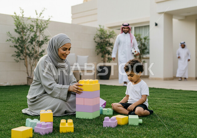 ايماءات السعادة والسرور بقضاء وقت ممتع مع الوالدة، الاستمتاع بتركيب المكعبات، ام عربية خليجية سعودية محجبة ترتدي عباءة بنية تلعب مع ابنها، مفهوم الأمومة والطفولة، رعاية وتشجيع وتطوير مهارات الأطفال، الاهتمام بالأبناء ودعمهم
