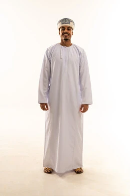 The emphasis on a neat appearance, the concept of masculinity and dignity, expressions of self-confidence, a portrait of a smiling Omani Gulf Arab man wearing a dishdasha and a turban, standing upright and looking at the camera with gestures of happiness and joy, full-body, white background.
