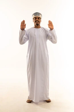 The palm is shown with the inner side facing up, looking at the camera with expressions of determination, conveying the concept of rejection and refusal. A young Arab Gulf Omani man wearing a dishdasha and a turban stands upright, raising his hands upwards, with a full-body view against a white background.