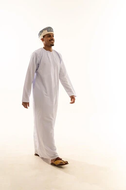 السير بخطى ثابتة نحو الأمام، ايماءات المشي و الذهاب إلى مكان معين، بورتريه من الجانب لرجل عربي خليجي عماني مبتسم يرتدي الدشداشة و العمامة ينظرامامه  بتعابير السعاده و السرور، صورة الجسم بالطول الكامل، خلفية بيضاء