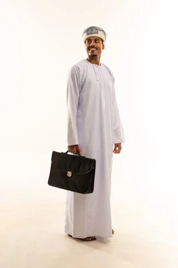 إشارات جسدية تعكس الحزم والثقة، الوقوف باستقامة والنظر إلى شيء ما، مفهوم لغة الجسد، بورتريه لرجل عربي خليجي عماني يرتدي الدشداشة و العمامة يحمل بيديه حقيبه العمل يقف باسقامة ، تعابير السعادة و السرور ، الجسم بالطول الكامل ، خلفية بيضاء