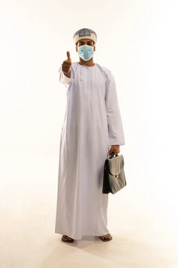 الشعور بالقبول والرضا، بورتريه لشاب عربي خليجي عماني يرتدي الدشداشة و العمامة و الكمامة يحمل حقيبة عمل فى يدية يرفع اصبع الابهام للاعلى بإيماءات الاعجاب والسرور، الجسم بالطول الكامل، خلفية بيضاء