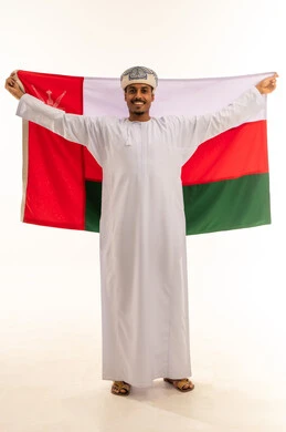 الاحتفال باليوم الوطني العماني 18 نوفمبر، أعياد ومناسبات وطنية، إظهار الولاء و الاخلاص والانتماء للبلاد، بورتريه لشاب عربي خليجي عماني يرتدي مبتسم العمامة والدشداشة يمسك العلم بايماءات الفخر، مفهوم حب الوطن، الجسم بالطول الكامل، خلفية بيضاء