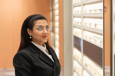 مفهوم الرؤية الواضحة، ماركات عالمية فاخرة، صورة مقربة لسيدة عربية خليجية اماراتيه ترتدي الزي الرسمي تقوم باختيار نظارة ملائمة لملامح الوجه، امرأة سعوديه تقوم بمعاينة النظارات، الاعجاب بالنظارات الطبية الجديدة، ضعف ونقص النظر