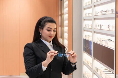 The positive impact of shopping on women, admiration for new eyeglasses, correcting and improving vision, the concept of poor vision, a close-up of a Saudi Arabian Gulf woman wearing formal attire choosing eyeglasses that fit her facial features, an Emirati woman examining eyeglasses