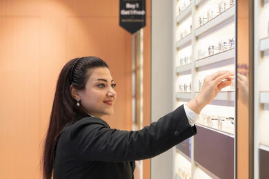 Clear vision concept, luxury international brands, close-up of an Emirati Gulf Arab woman wearing formal attire choosing glasses that fit her facial features, a Saudi woman examining glasses, admiring new eyeglasses, weak and deficient vision