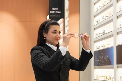 Luxury international brands, vision improvement and correction, concept of poor vision, close-up of an Emirati Gulf Arab woman wearing formal attire choosing glasses that suit her facial features, a Saudi woman examining glasses, admiring new medical glasses,
