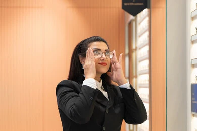 Correcting and improving vision, shopping in Emirati stores, expressions of self-confidence, the concept of weak vision, purchasing new eyeglasses, a close-up of a veiled Saudi Arabian Gulf woman wearing formal attire choosing eyeglasses that suit her facial features, an Emirati woman examining eyeglasses