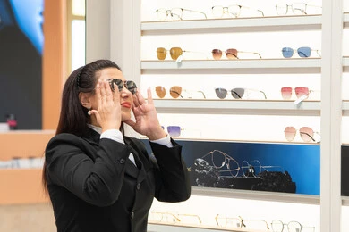 التأثير الإيجابي للتسوق على المرأة، اكسسوارات نسائية عصرية، الاهتمام بالمظهر الخارجي، تجربة النظارات الشمسيه قبل الشراء، امرأة اماراتية تقوم باختيار نظارة شمسيه مناسبة، سيدة عربية خليجية سعودية ترتدي الزي الرسمي تقوم بقياس نظاره