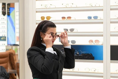 اكسسوارات نسائية عصرية، الاهتمام بالمظهر الخارجي، التأثير الإيجابي للتسوق على المرأة، تجربة النظارات الشمسيه قبل الشراء، امرأة اماراتية تقوم باختيار نظارة شمسيه مناسبة، سيدة عربية خليجية سعودية ترتدي الزي الرسمي تقوم بقياس نظاره