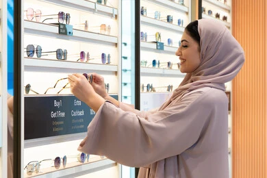 الاهتمام بالمظهر الخارجي، أحدث الاكسسوارات النسائية، المتعة بالتسوق في مولات الإمارات، مواكبة آخر صيحات الموضة والجمال، شابة عربية خليجية اماراتية محجبة ترتدي عباءة تقوم باختيار نظارة شمسية ملائمة لملامح الوجه،  امرأة سعودية تقوم بمعاينة النظارات