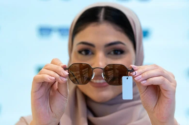 اكسسوارات نسائية عصرية أنيقة، النظر إلى الكاميرا بإيماءات السرور، اقتناء واختيار نظارة شمسيه مناسبة، الاستمتاع بالتسوق في الإمارات، امرأة اماراتية تقوم بتجربة النظارات قبل الشراء، صورة مقربة لشابة عربية خليجية سعودية محجبة ترتدي عباءة تقوم بقياس نظاره