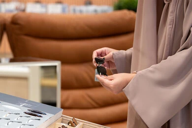 Taking advantage of offers and discounts, taking care of one's appearance, keeping up with the latest fashion and beauty trends. A close-up of the hands of a young Arab Gulf Emirati woman choosing sunglasses that suit her facial features. A Saudi woman examining glasses.