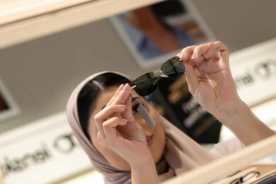 تجربة النظارات الشمسيه قبل الشراء، التسوق في المولات والمتاجر الإماراتية، انواع وماركات عالميه، سيدة سعودية تقوم باختيار نظارة شمسيه مناسبة، صورة مقربة لامرأة عربية خليجية إماراتية محجبة مبتسمة ترتدي عباءة تقوم بقياس نظاره بإيماءات السعادة والسرور