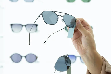 Shopping in one of the malls in the Emirates, a sunglasses exhibition, taking advantage of offers and discounts, keeping up with the latest fashion and beauty trends, a close-up of the hands of a young Arab Gulf Emirati woman choosing sunglasses that suit her facial features, a Saudi woman examining the glasses