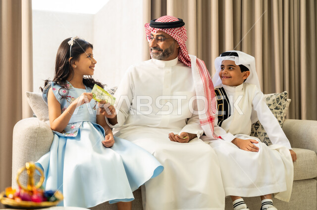 فرحة وبهجة الابناء في ايام العيد السعيد، حسن اكرام واستقبال الضيف, صلة الرحم والترابط الاسري, التجمعات والزيارات الاسرية في الأعياد والمناسبات الاسلامية المباركة, إيماءات الفرح والسرور بالأحفاد، رجل عربي خليجي سعودي يقوم بتقديم العيدية لحفيدته