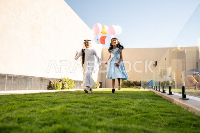 Happy Islamic holidays and occasions, children's joy and happiness with the arrival of Eid, enjoying with sisters in the open air with gestures of cheerfulness and happiness, a Saudi Arabian boy and girl running in one of the chalets and tourist resorts, enjoyable moments filled with expressions of joy