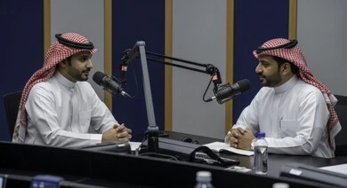  معدات وأجهزة تسجيلات الصوت، اجراء بث صوتي مباشر ( بودكاست ) عبر برامج التواصل الاجتماعي، ايماءات الحماس والتفاعل، تعابير السعادة والسرور، رجل عربي خليجي سعودي يرتدي الثوب والشماغ التقليدي مع رجل بالبدلة الرسمية في مقابلة عمل داخل مقر الشركة
