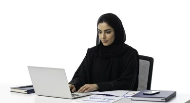 مهنة ووظيفة نسائية مكتبية سعودية، ادارة وانجاز المهام باستخدام جهاز تقني حديث ومتطور, بورتريه مقرب لإمرأة عربية خليجية سعودية مبتسمة ترتدي الحجاب والعباءة تعمل على الحاسوب المحمول، ايماءات وتعابير السرور والسعادة، خلفية بيضاء