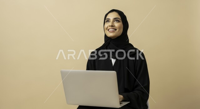  مهنة ووظيفة نسائية مكتبية سعودية، ادارة وانجاز المهام باستخدام جهاز تقني حديث ومتطور, بورتريه مقرب لإمرأة عربية خليجية سعودية مبتسمة ترتدي الحجاب والعباءة تعمل على الحاسوب المحمول، ايماءات وتعابير السرور والسعادة، خلفية بيج