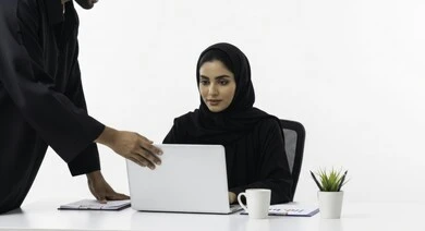 Saudi female office profession and job, managing and completing tasks using a modern and advanced technical device, close-up portrait of a smiling Saudi Arabian Gulf woman wearing hijab and abaya working on a laptop, gestures and expressions of pleasure and happiness, white background