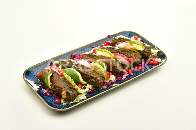 طبق من  لفائف اليالنجي مع الحشوة الغنية بالتوابل والنكهات الشهية، فنون تقديم الطعام في مطابخ المملكة العربية السعودية، وصفة الطعام التقليدية، ورق العنب المحشو بالخضار الطازجة، وجبة شعبية لذيذة، المأكولات الشرقية المشهورة، خلفية بيضاء