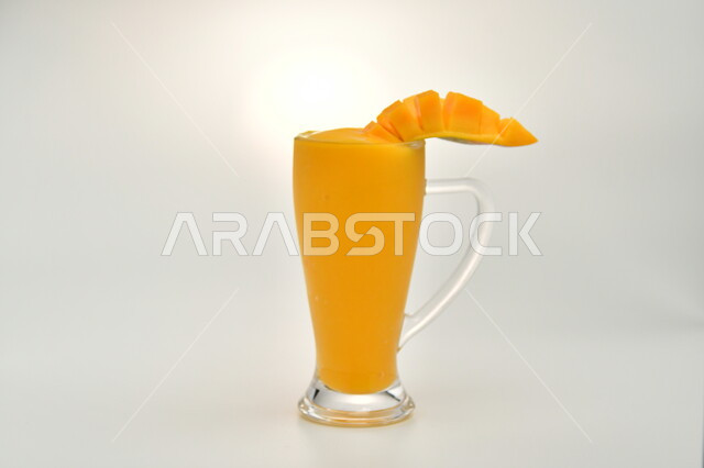 Healthy, beneficial and nutritious drink, refreshing seasonal fresh fruit juice, delicious cold natural cocktail, Saudi local agricultural crops and fruits, a glass of delicious mango juice, white background