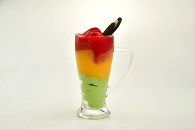 Delicious cold desserts, foods and meals full of sugar and high calories, a cup of fruit salad filled with fresh fruits, cream and delicious nuts, white background