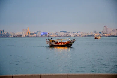 Architectural engineering art of building towers and skyscrapers, wooden boat sailing in Doha city during the day, buildings and facilities overlooking the sea, famous tourist places and landmarks in Qatar, attracting and attracting tourists from all over the world