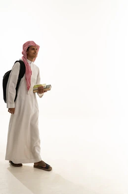 The concept of diligence to achieve success, gestures of walking and going to a specific place, educational scientific curricula, the concept of returning to school, a portrait of an Arab Gulf Saudi student wearing a white thobe and a shemagh, carrying a backpack and school books, looking with gestures of happiness and joy, a full-body image, white background.